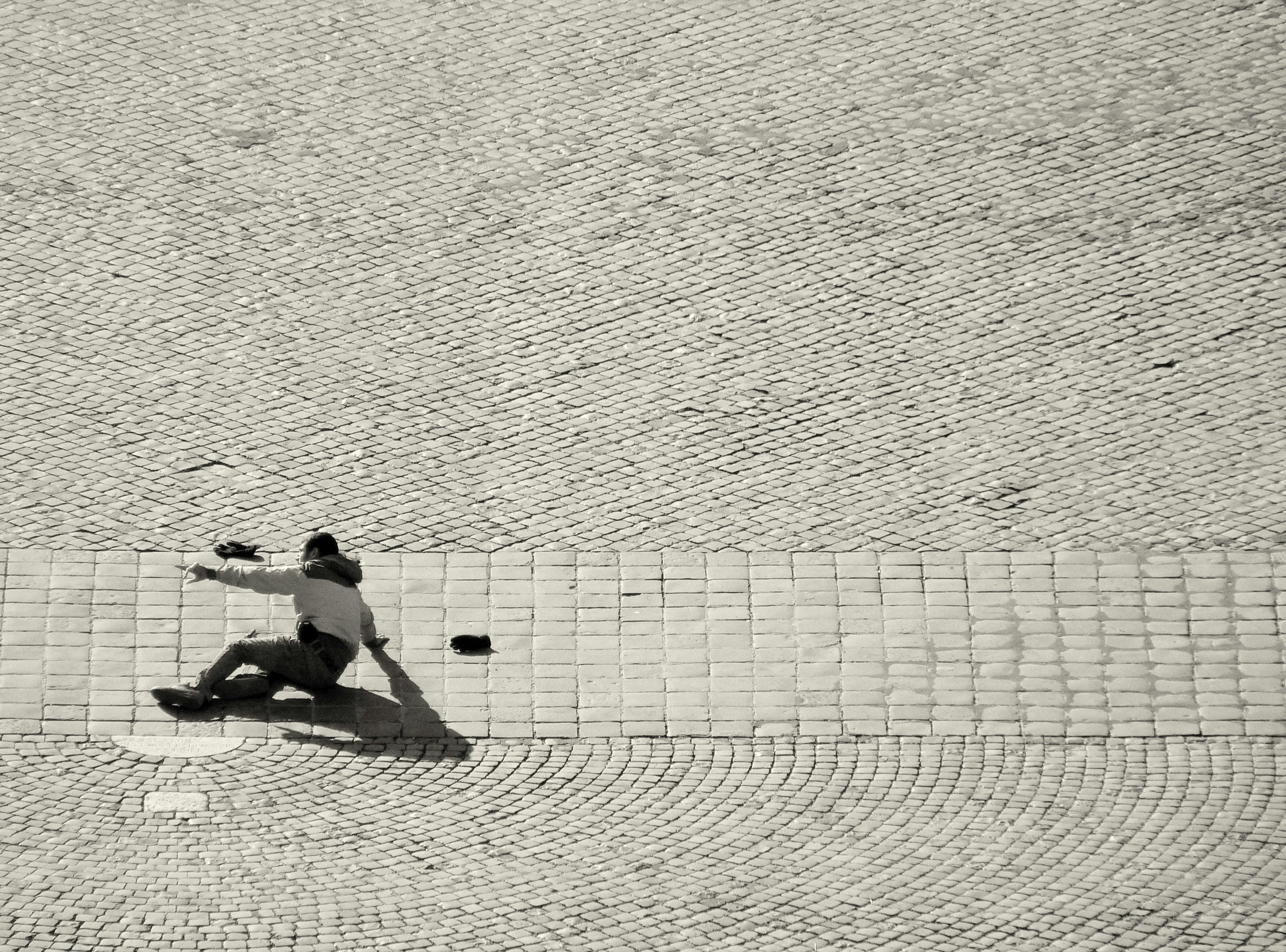 man in black shorts sitting on white concrete wall during daytime